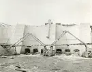 Byggandet av Älvkarleby kraftverk med dammstrukturen där tunga träställningar krävdes för att bära upp konstruktionen innan betongen härdat, omkring år 1906 (enligt text i album).