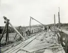 Byggandet av Älvkarleby kraftverk där bygget av fångdamm pågår för att torrlägga strömfåran så att arbetarna kunde gjuta det permanenta betongdammarna direkt på berggrunden, omkring år 1906 (enligt text i album).