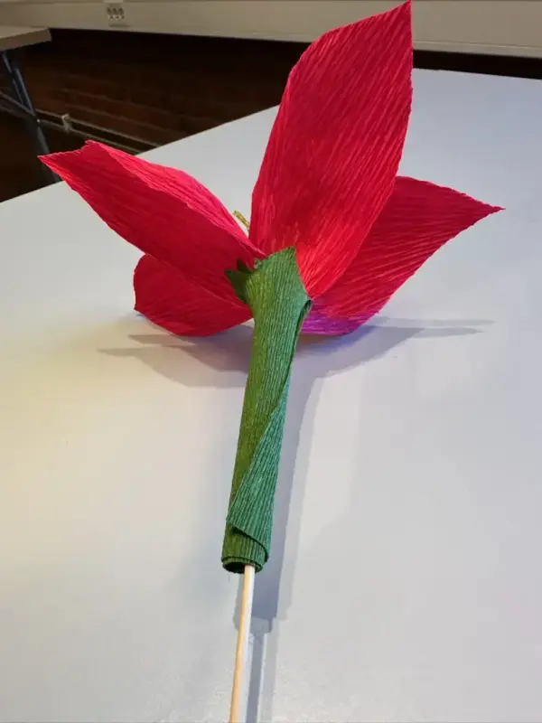 En rosa papirblomst blir montert.