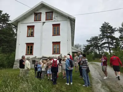 Menneskegruppe foran stort hvitt hus