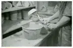 Tillverkningsprocessen hos Bo Fajans, omkring 1946-1950. Arbetsstation för glasering av godset genom doppning.