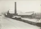 Fabriksbyggnad med skorsten och skylten 