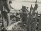 Sjösättning av mindre båt med hjälp av kärra på slip av trä.