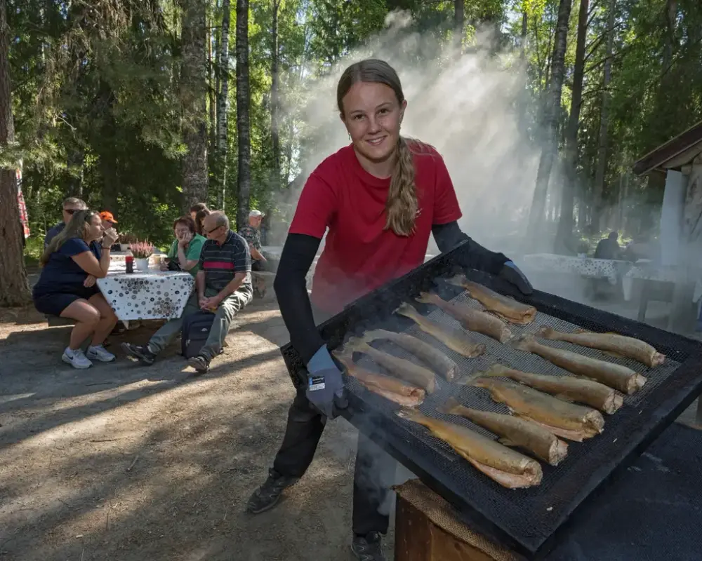 En ung kvinne holder et brett med røkt fisk under fiskerøyking på De nordiske jakt- og fiskedagene.