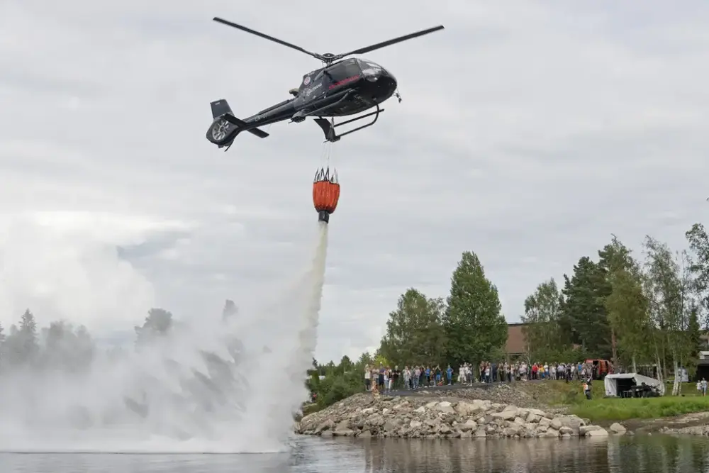 Et helikopter slipper vann over en innsjø mens publikum ser på under De nordiske jakt- og fiskedagene.