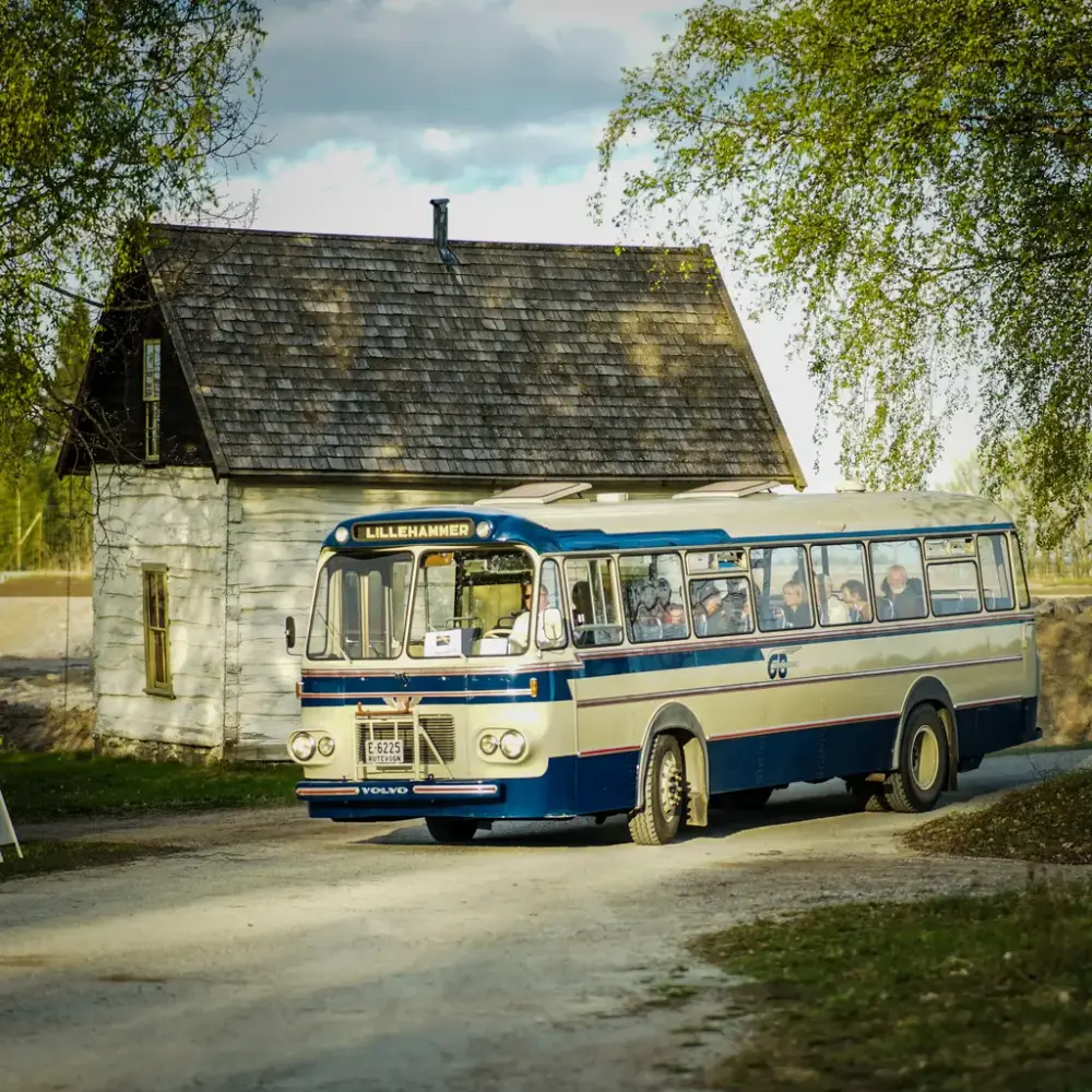En veteranbuss utenfor tømmerhus i friluftsmuseet på Norsk utvandrermuseum