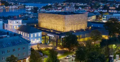 kveldsbilde i fugleperspektiv av Kristiansund sentrum, med det kubeformede, opplyste kulturhuset Normoria i fokus for bildet