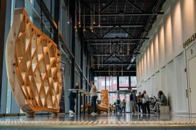 høy, lys foajé i kulturhus, der mennesker sitter og står i bakgrunnen.