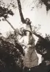 Två flickor i sommarklänningar m.m. har hoppat upp i en björk. 
Möjl. Ruth Svensson och hennes lillasyster Blenda Maria.