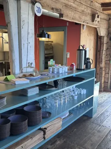 Vi ser her en kafedisk i turkis farge, fylt med tallerker og lass under disken, mens det på disken er kaffe og biscotti 