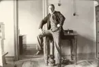 En ung man poserar på ett kontor, halvt sittande på ett skrivbord.
Trol. Seved Svensson på postkontoret i Skurup, dit han flyttade för att arbeta i december 1917.