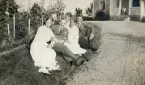 En grupp ungdomar har slagit sig ner på gräsvallen i en trädgård.  5:e fr. vänster trol. Ruth Svensson. Längst bak (skymd) möjl. hennes bror
Yngve.