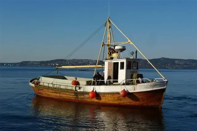 Vi ser en båt, med styrhuset ganske langt fremme og et stort lasteplan, hvor 2/3 nok er under vannskorpen. 