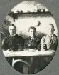 En medelålders kvinna och två män sitter i en soffa och betraktar fotografen,