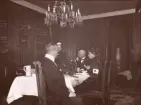 Foto från Hofors herrgård; Hedvig Ulfsparre (till höger i bild) i sin Röda Korset sjuksköterskeuniform, disponent Per Eriksson brevid henne följt av en ej namngiven kvinna brevid honom. Möjligen Hedvigs far John Axel Ulfsparre i förgrunden med ryggen mot kameran.