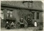 Exteriörbild av fröknarna Ulfsparres hem med trädgård, Östra Storg. 74, Jönköping. Framför huset syns sex kvinnor, fyra av dem äldre, samt en yngre man.