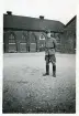 Bengt Hultin på kaserngården med grötrock m/ träng (?). Kvibergs kaserner i Göteborg (enligt text i album och baksida kort).