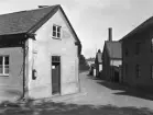 Nedslag i Linköping 1937 och till en miljö som utstått vissa förändringar. Placerad i bilden hade man en gång i tiden sagt sig stå i skärningen av Biskopsgatan och Tornbygatan. Sedan en längre tid var nu samma stråks namn Å- och Gråbrödragatorna. Byggnaden till vänster kvarstår ännu och ingick i äldre tid i Domkyrkoförsamlingens sysslomansboställe. Länge inrymde gården även Jubergs Hyrkuskverk. Husraden till höger är till större delen borta.
