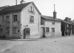 Miljön utmed Östgötagatan i höjd med Hunnebergsgatan i Linköping. In på gården till de rappade husen hade plåtslagare Ivar Jonson sin verkstad. Notera frukt- och grönsaksautomaten invid hörnhuset. Foto 1937 eller möjligtvis 1938.