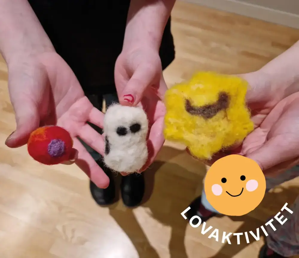 Två par händer håller upp tre olika figurer i ull med olika färger.