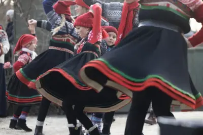 Barn og unge i setesdalsbunader og røde nisseluer danser folkedans.