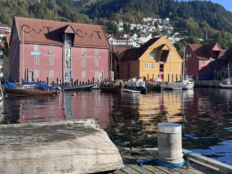 Vi ser de vakre sjøbodene som huser Norges Fiskerimuseum fra sjøsiden, med båter duppende i vannet foran. 