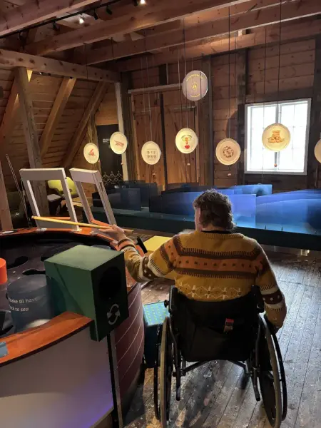 Vi ser en mann i rullestol som fikser i fiskedammen 