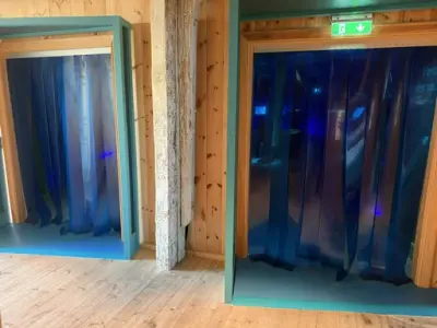 Vi ser to blå dørkarmer som er inngangen til utstillingen Verden under vann, her er det plastlameller i døråpningen for å hindre varmetap. 