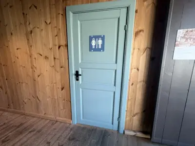 Bildet viser en dør, med skilt for toaletter, og innenfor denne er det to toaletter tilgjenglig, men ingen av dem for rullestol